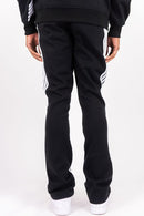 Black track pants with white three-stripe detailing on the sides, shown from the back on a model wearing a black sweatshirt and white sneakers against a white studio background. By Fresh N Fitted 
