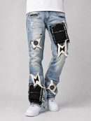 Light blue distressed denim jeans with black patchwork fabric panels and white embroidered star patches, shown on a model from the waist down against a light gray studio background.