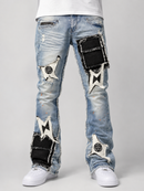 Light blue denim jeans with distressed details, frayed edges, and large black and white patch designs on the thighs and lower legs, shown on a model from the waist down wearing white sneakers against a light gray background.