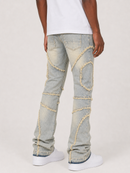 A person shown from the back wearing light-wash distressed denim jeans with decorative frayed patch details, a white T-shirt, and white sneakers against a plain light gray studio background.