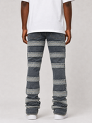 A person shown from the back wearing dark blue denim jeans with horizontal light gray and faded denim stripe panels, paired with a white t-shirt and white sneakers, against a light gray studio background.