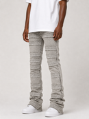 A person wearing light gray pleated denim jeans with a white t-shirt and white sneakers, shown from the waist down against a light gray studio background.