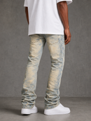 A person shown from the back wearing light-wash blue and beige acid-wash jeans, a white t-shirt, and white sneakers against a gray studio background.