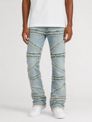 A person wearing light-wash blue jeans with diagonal stitched paneling and frayed detailing, paired with a white t-shirt and white sneakers, shown against a plain light gray studio background.