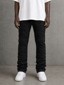 A person wearing distressed black jeans with diagonal frayed detailing, paired with a white t-shirt and white sneakers, standing against a textured gray wall.