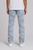 Light wash blue jeans with diagonal stitched panel details on the legs, shown on a model from the back wearing a white t-shirt and white sneakers against a light gray background.