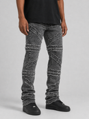 A person wearing distressed gray denim jeans with diagonal frayed patch details, a black t-shirt, and black sneakers, photographed against a light gray studio background.
