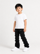 A young boy modeling a white crewneck t-shirt and black distressed ruffled jeans with white sneakers, standing against a plain white studio background.