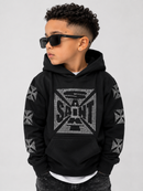 A child wearing a black hoodie with a large silver rhinestone 'SAINT' graphic on the chest and matching silver cross motifs on the sleeves, styled with black sunglasses against a light gray background.