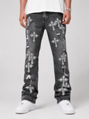 A person wearing distressed black denim jeans with multiple white cross patches and white sneakers, photographed against a light gray studio background.