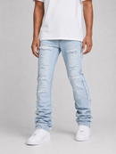 A person wearing light-wash, heavily distressed skinny jeans with ripped details and frayed edges, paired with a white t-shirt and white sneakers, against a neutral gray studio background.