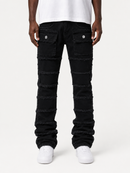 A person wearing black distressed denim jeans with horizontal frayed seam details, paired with a white t-shirt and white sneakers, shown from the waist down on a light gray studio background.