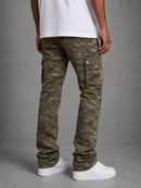 A person shown from the back wearing slim-fit camouflage cargo pants, a white t-shirt, and white sneakers against a gray concrete-textured studio background.