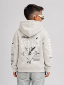 A child model shown from the back wearing a light beige Givenchy hoodie with a large graphic print on the back and sleeves, paired with light-wash jeans against a light gray studio background.