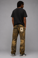A model shown from the back wearing a pair of heavily distressed, acid-washed brown jeans with a raw-edge paper patch on the back pocket, a black t-shirt, and sneakers, against a solid gray studio background. By Fresh N Fitted