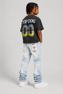 A child model shown from the back wearing a faded black graphic t-shirt with 'TOP DOG' and '00' on the back, paired with light-wash blue jeans and white sneakers, against a light gray studio background. by Fresh N Fitted