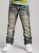 A pair of washed light tint denim jeans with distressed knee patches and gathered cuffs, shown on a model wearing white sneakers against a light gray studio background. By Fresh N Fitted.