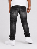 Rear view of a person wearing faded black denim jeans with a white t-shirt and white sneakers against a light gray studio background.