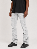 A person wearing light gray distressed denim cargo pants with ripped details and black sneakers, shown from the waist down against a plain light gray studio background.