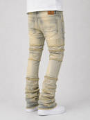 Ripped light-wash denim jeans with frayed patch details and ruffled cuffs, shown on a model from the back against a light gray background.