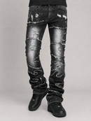 Distressed black denim jeans with heavy fading and ripped details, shown on a model from the waist down against a light gray studio background.