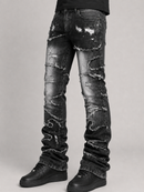 Distressed black denim jeans with heavy fading, rips, and frayed edges, shown on a model from the waist down wearing black shoes against a light gray studio background.