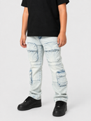 A child wearing light-wash distressed cargo jeans with multiple flap pockets, a black t-shirt, and black sneakers, standing against a light gray studio background.