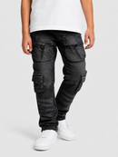 A person wearing washed black cargo jeans with multiple flap pockets, paired with a white t-shirt and white sneakers, shown from the waist down on a light gray studio background.