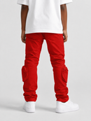 A person shown from the back wearing bright red cargo pants with large knee pockets, a white T-shirt, and white sneakers against a light gray studio background.