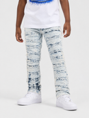 A child wearing light blue heavily distressed denim jeans with horizontal frayed cuts, styled with a white graphic t-shirt and white sneakers against a light gray studio background.