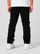 Rear view of a person wearing black jeans with frayed side details and white sneakers against a light gray studio background.