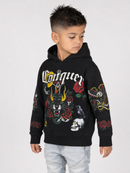 A young boy wearing a black Conquex hoodie with colorful graphic prints of a panther, roses, skulls, and snakes, paired with light wash jeans, photographed against a light gray studio background.