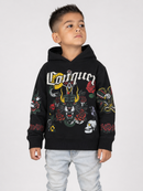 A young boy wearing a black hoodie with a detailed multicolor graphic print featuring a tiger, roses, skulls, and the word 'Conquer' in gothic lettering, paired with light wash jeans, photographed against a light gray studio background.