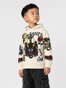 A young boy wearing a cream-colored Carrouge hoodie with a detailed black, red, and yellow graphic print on the front and sleeves, paired with dark cargo pants, set against a plain light gray background.