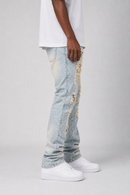 A person shown from the waist down wearing light-wash distressed denim jeans with ripped details and frayed edges, paired with a white t-shirt and white sneakers, against a light gray studio background.