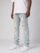 Light wash blue distressed jeans with ripped details showing beige patches, worn by a model with a white t-shirt and white sneakers against a light gray background.