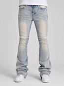 Light-wash blue distressed jeans with a faded yellow-tinted wash and ripped details, shown on a model from the waist down wearing white sneakers against a light gray studio background.