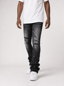 A person wearing faded black jeans with a white t-shirt and white sneakers, shown from the chest down against a light gray studio background.