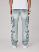 A person shown from the back wearing light-wash blue cargo jeans with multiple flap pockets and buckle details, a white t-shirt, and white sneakers against a light gray studio background.