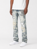 A person wearing light blue distressed denim jeans with white star patches, embroidered floral details, and ripped sections, paired with a white t-shirt and white sneakers, shown against a plain light gray studio background.