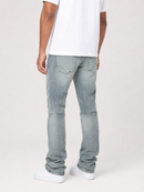 A person shown from the back wearing light-wash blue denim jeans, a white t-shirt, and white sneakers against a plain light gray studio background.