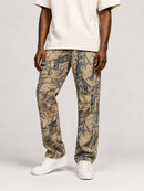 A person wearing slim-fit camouflage pants in tan, brown, and gray, paired with a cream t-shirt and white sneakers, shown from the waist down against a light gray studio background.