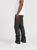 A side profile view of a person wearing dark gray slim-fit jeans, a white t-shirt, and white sneakers against a light gray studio background.