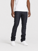 A person wearing slim-fit dark indigo jeans, a white t-shirt, and white sneakers, standing against a light gray studio background.