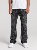 A person wearing black denim jeans with a white abstract wavy pattern, styled with a white t-shirt and white sneakers against a light gray studio background.